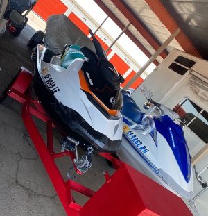 Two Seadoo GTI 130 & Yamaha VX 110 Sport jet skis parked in a garage.