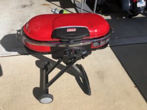 A red grill sitting on top of a cement floor.