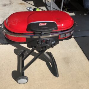 A red grill sitting on top of a cement floor.
