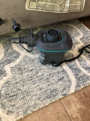 A vacuum is sitting on the floor next to a rug.