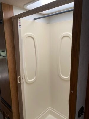 A shower in a 2000 Itasca Spirit 31' with a door open.