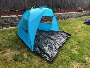 A blue tent is sitting in the grass.