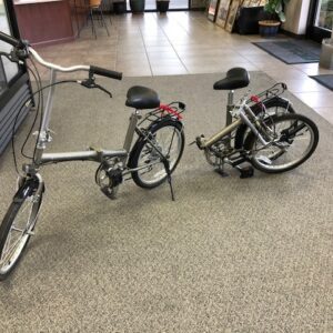 Two bikes parked on the floor of a building.