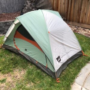 A tent is pitched in the backyard of a house.