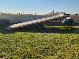 2021 Diamond Flat Bed 24' Trailer w/tilt and winch parked in a grassy area.