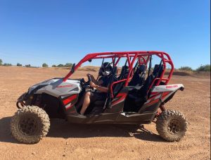 A man is riding a 2017 Maverick Can-Am 4 person utv in the desert.