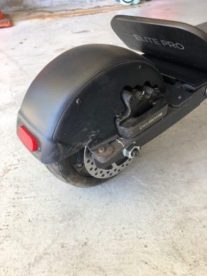 A black Add Two Electric Cycleboard is parked in a garage.