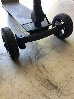 A black Add Two Electric Cycleboards with wheels in a garage.