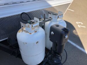 Two propane tanks are next to a car.