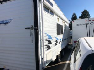 A white rv parked next to a car.