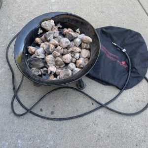 A Add Gas Fire Pit with rocks and a bag on the ground.