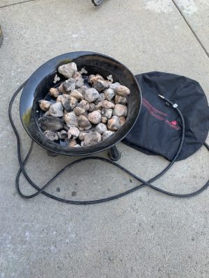 A Add Gas Fire Pit with rocks and a bag on the ground.