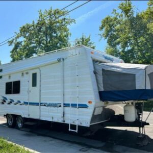 A white trailer with blue awning parked on the side of road.