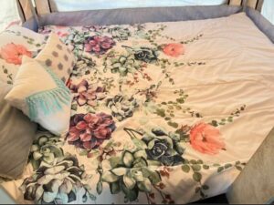 A bed with floral print sheets and pillows.