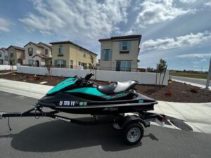 A jet ski is parked on the street near some houses.