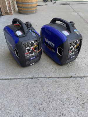 Two Add 2K Watt Yamaha generators that pair together sitting on a concrete floor.