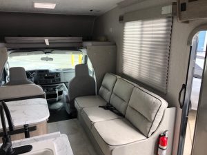 The interior of a 2021 Coachmen Freelander 30' Class C with a couch and a sink.