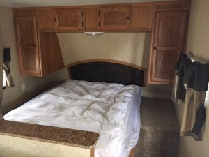 A 2011 Rainier Dutchman Bunk House 28' with a bed and cabinets.