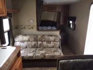 The interior of a 2011 Rainier Dutchman Bunk House 28' with a couch and a kitchen.