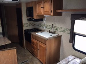 A kitchen in a 2011 Rainier Dutchman Bunk House 28' with a sink and microwave.