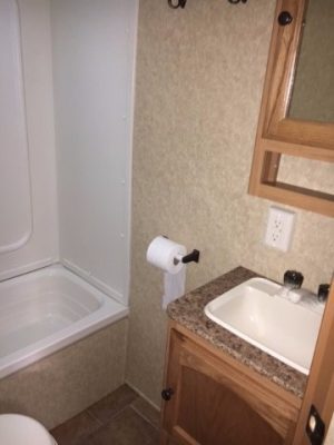 A small bathroom with a 2011 Rainier Dutchman Bunk House 28' and sink.