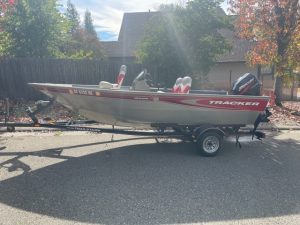 A 2003 Tracker Outboard Fishing Boat 16' is parked in front of a house.