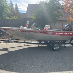 A 2003 Tracker Outboard Fishing Boat 16' is parked in front of a house.