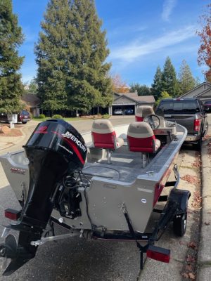 The 2003 Tracker Outboard Fishing Boat 16' is parked in the driveway of a house.