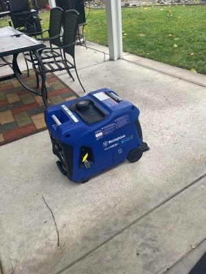 A blue generator sitting on a concrete patio.