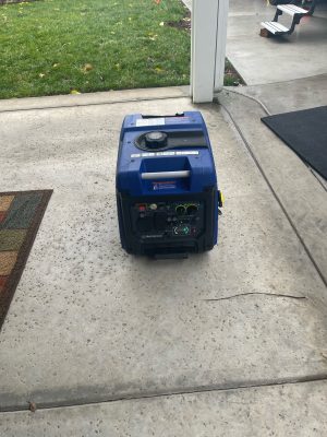 A generator sitting on the ground in front of a house.