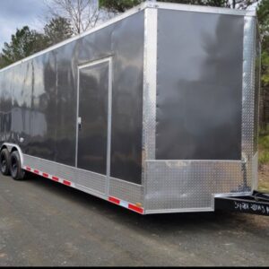 A black trailer with a silver trim parked on the side of a road.