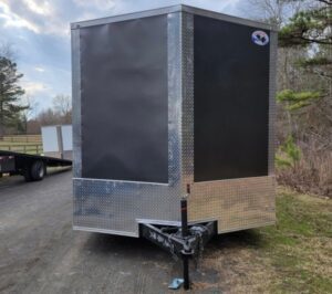 A black and silver trailer parked on the side of a road.