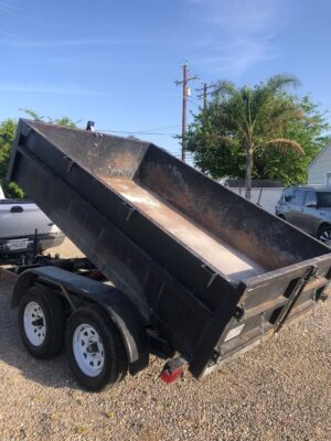 A dump trailer with the back open on top of it.