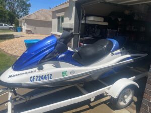 A blue and white jet ski parked in the driveway.