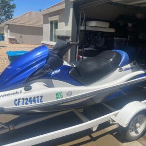 A blue and white jet ski parked in the driveway.
