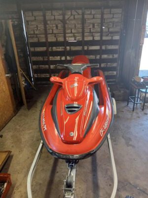 A red jet ski parked in the middle of a garage.
