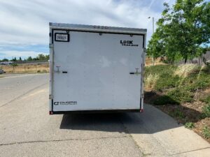 A white trailer parked on the side of a road.