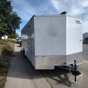 A white trailer parked on the side of a road.