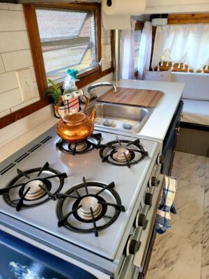 A stove with three burners and a cutting board on top.