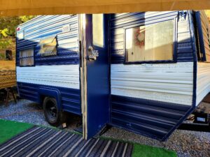 A blue and white trailer with a door open.