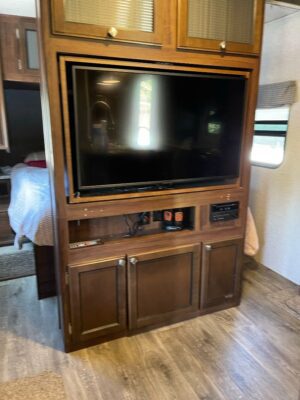 A large television is on the top of a wooden cabinet.