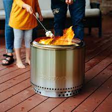 A couple of people standing around a fire pit.