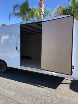 A white trailer with sliding doors and a black frame.