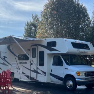 A white rv parked in the driveway of a house.