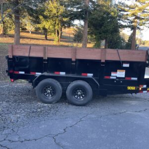 A black dump trailer with wood sides parked in the street.