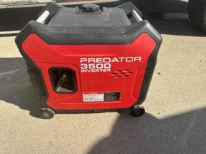 A red and black generator sitting on the ground.