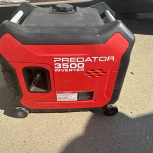 A red and black generator sitting on the ground.