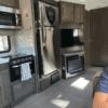 A kitchen with a refrigerator, microwave and oven.