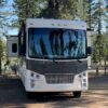 A white and gray rv parked in the woods.