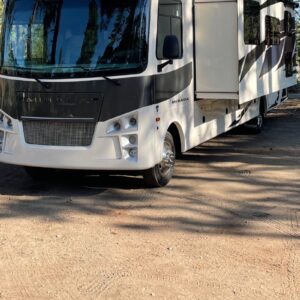 A white and black rv parked in the sun.